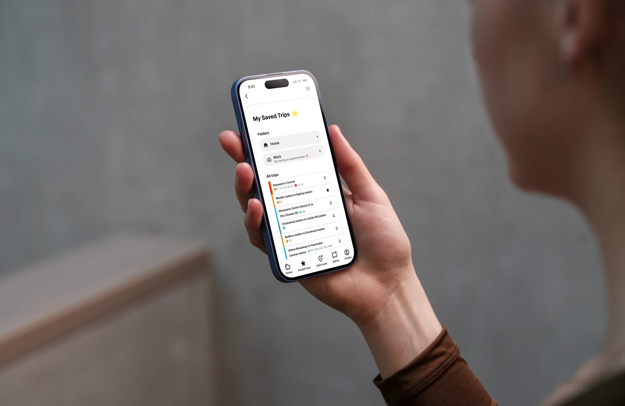 Someone holding a phone showing the My Saved Trips screen